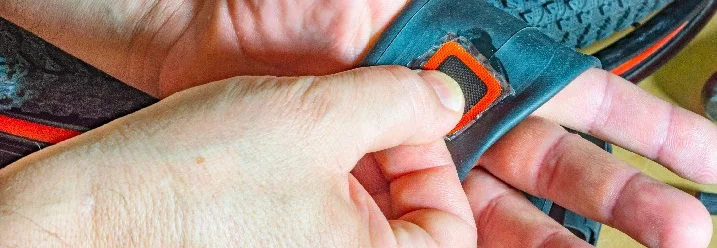 Hände halten einen Fahrradschlauch mit einem Flicken